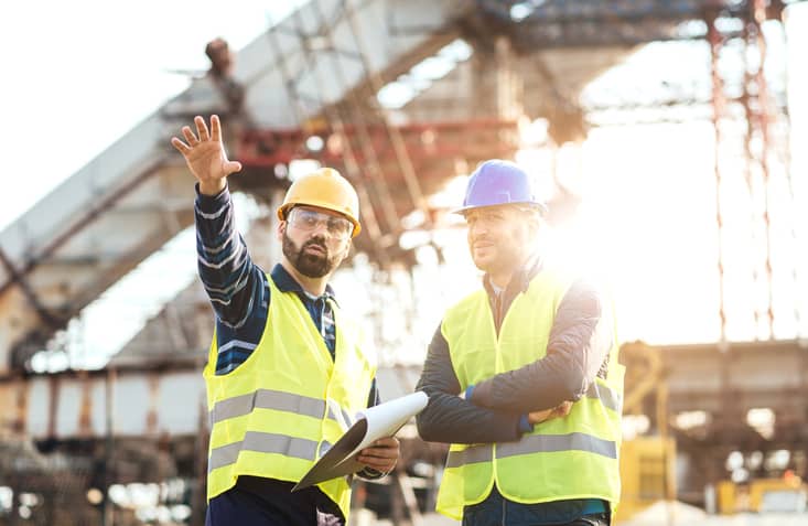 Image of two men working on a building site who use a construction answering service