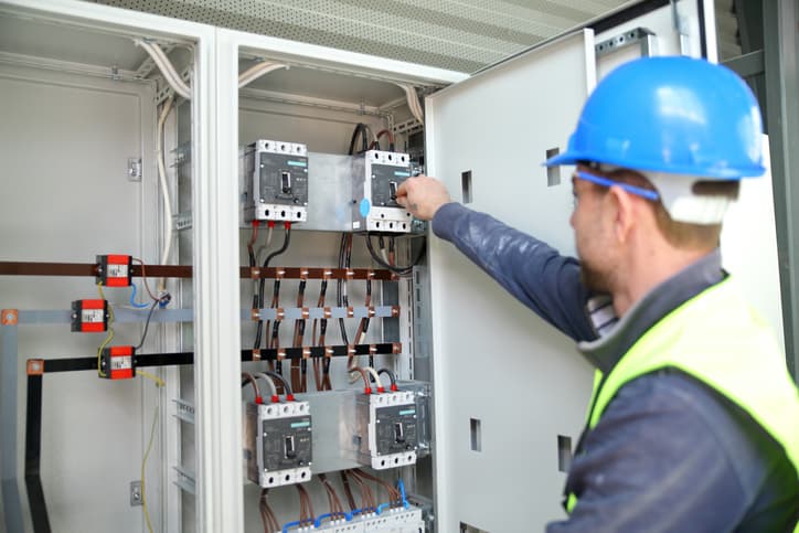 Image of a man working with an electrical box that uses an electrician answering service
