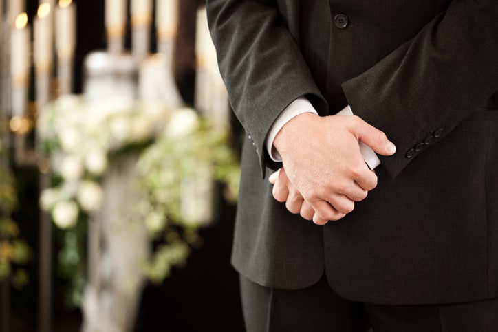 Image of a funeral director who uses a funeral home answering service crossing his hands during a ceremony.