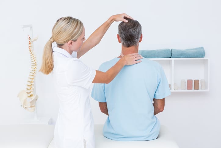Image of a man getting his neck examined in a chiropractic office by a professional who uses a chiropractor answering service